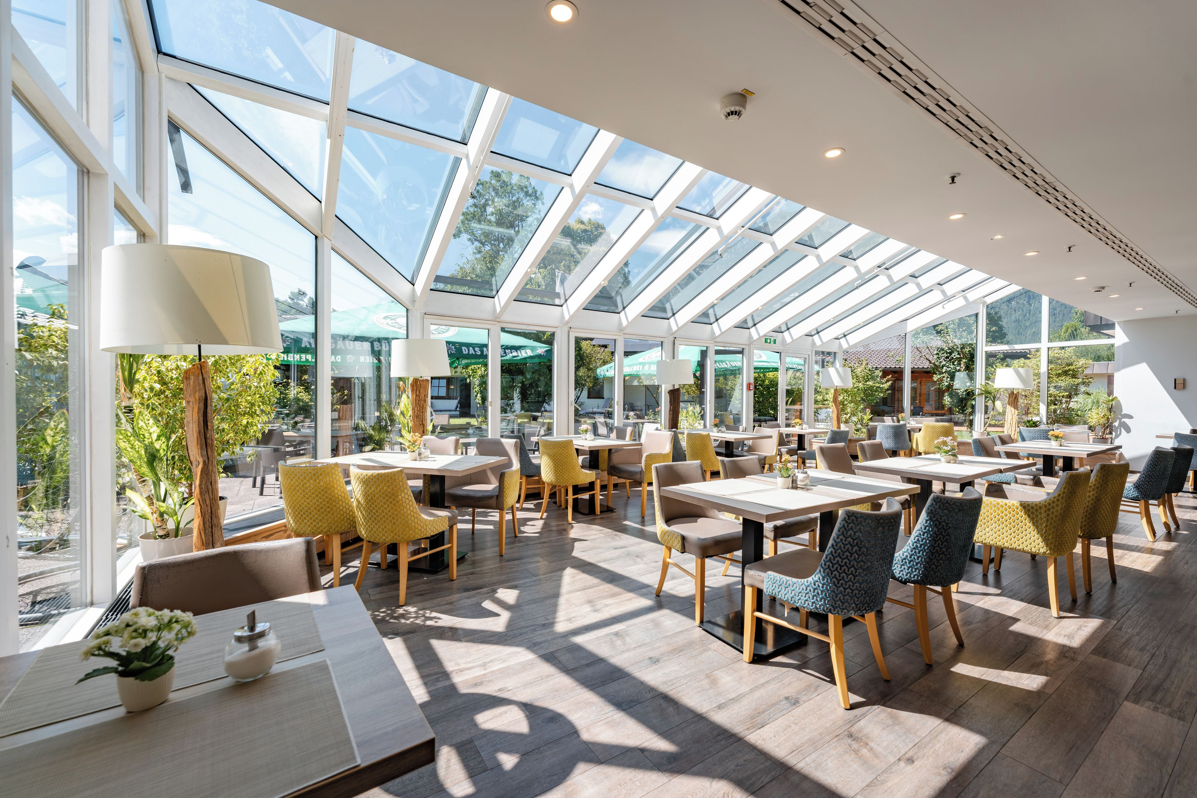 A spacious indoor area with tables and chairs, large windows, and a view of the outdoors.
