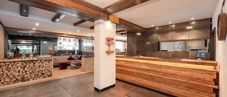 A modern interior with a reception desk, seating area, and a bar.