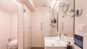 A modern bathroom with a glass shower enclosure, a white sink, and a mirror with a 'SAVE WATER' sign.