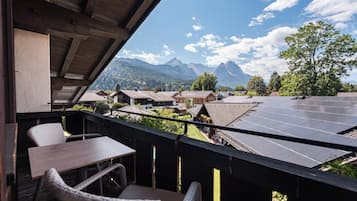 Un balcón con vistas a una cadena montañosa, paneles solares y edificios tradicionales.