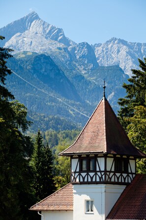 A traditional half-timbered building with a steeply pitched roof, set against a backdrop of snow-capped mountains and a clear sky. - LA GAP Alpin Boutique Hotel (Garmisch-Partenkirchen)