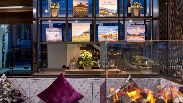 A modern interior with a fireplace, seating area, and a display of framed pictures. - HYPERION Hotel Garmisch – Partenkirchen (Garmisch-Partenkirchen)