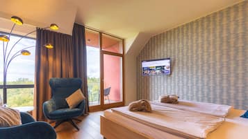 Une chambre d’hôtel avec un lit, une chaise, une télévision et une vue sur l’extérieur.