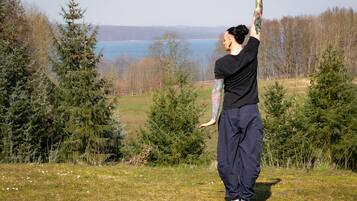 A person practicing yoga outdoors with a lake and trees in the background.