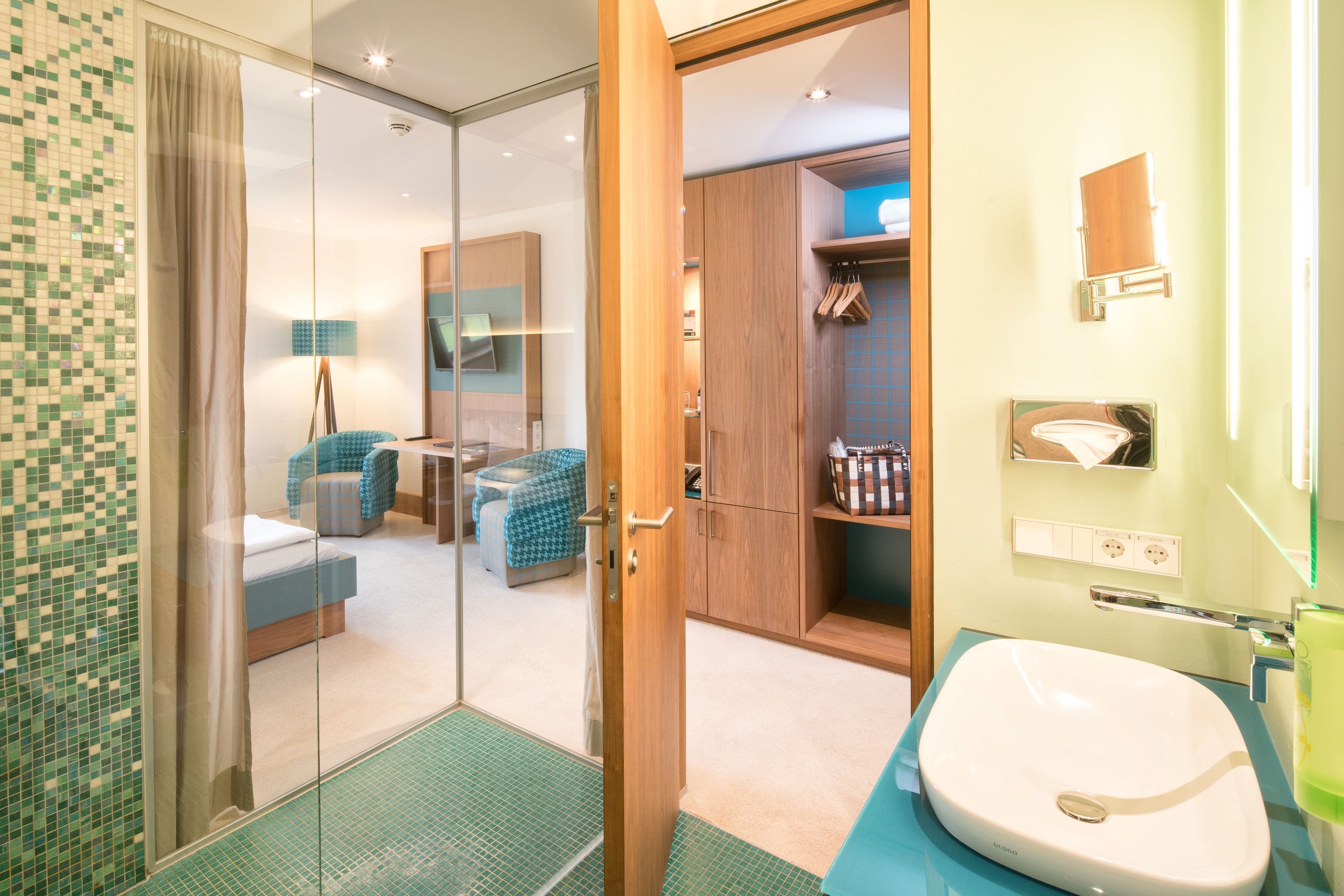 Een moderne badkamer met een douchecabine van glas, een witte wastafel en een blauw aanrecht.