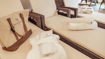 Habitación de hotel con una tumbona, una toalla blanca y un bolso color beige.