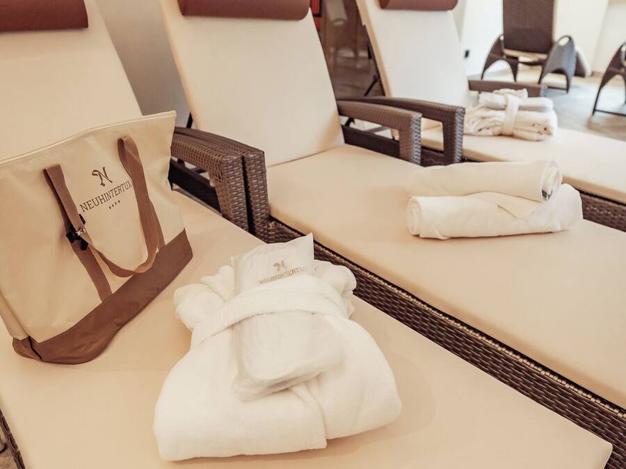 Habitación de hotel con una tumbona, una toalla blanca y un bolso color beige.