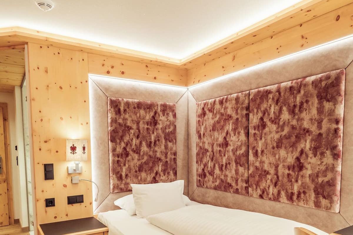 Un dormitorio con una cama grande, cabecera de madera, mesita de noche y una silla.