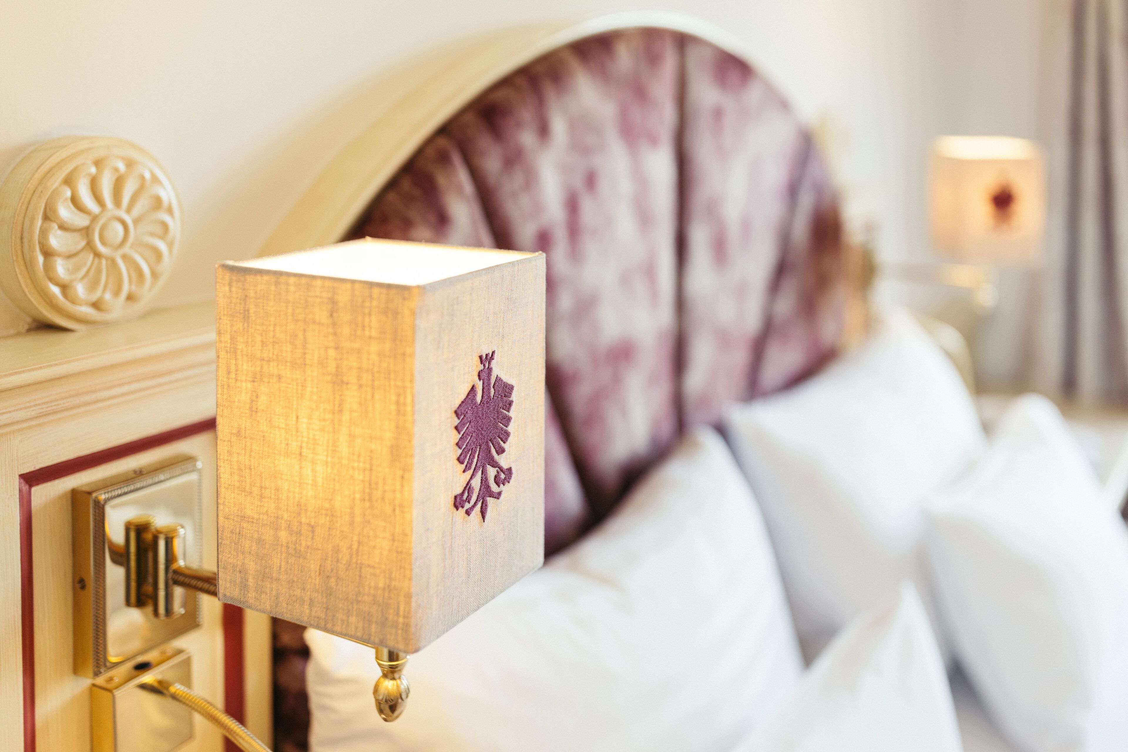 A neatly made bed with white linens and a decorative headboard.