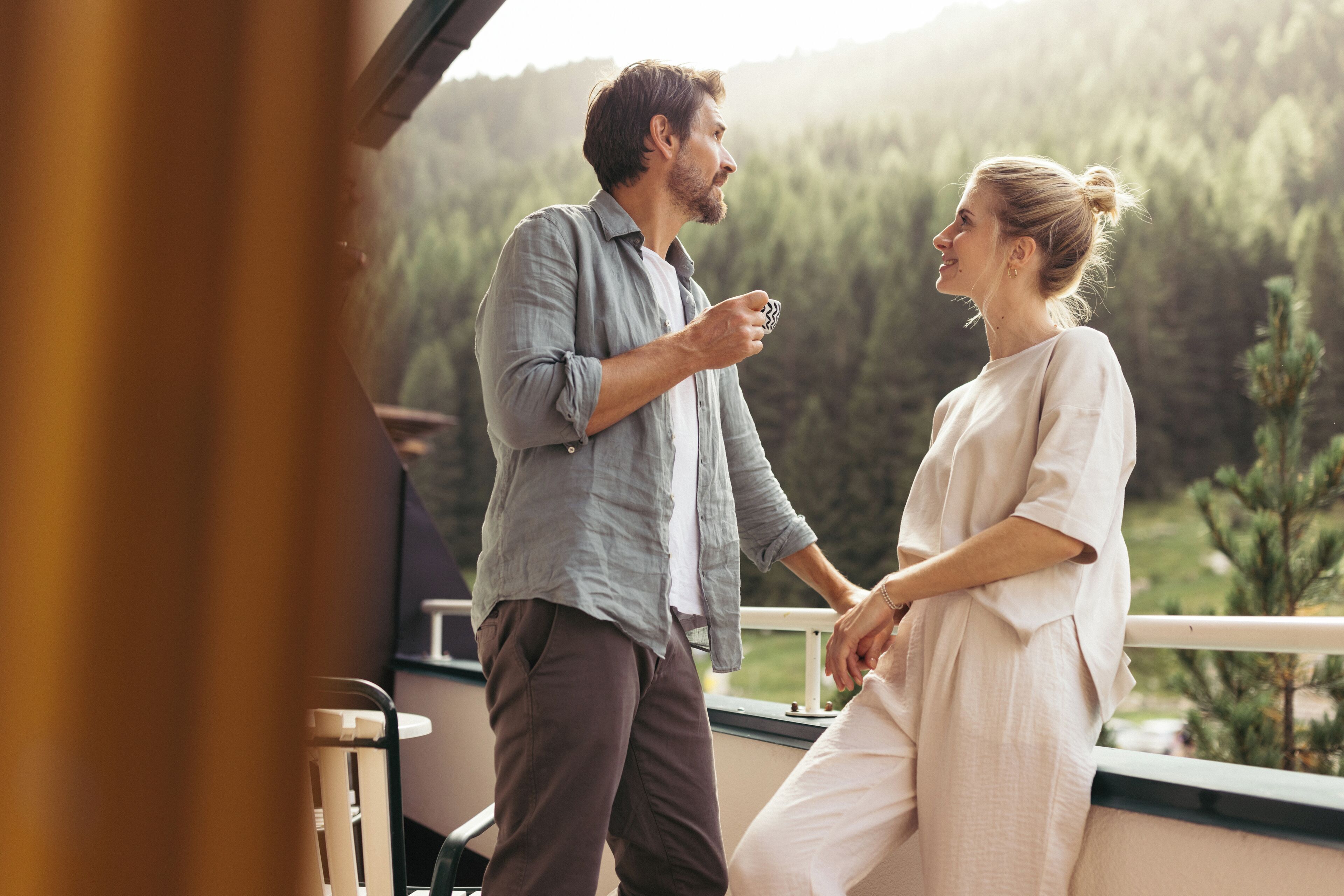 Ein Paar auf einem Balkon mit Blick auf eine bewaldete Landschaft.
