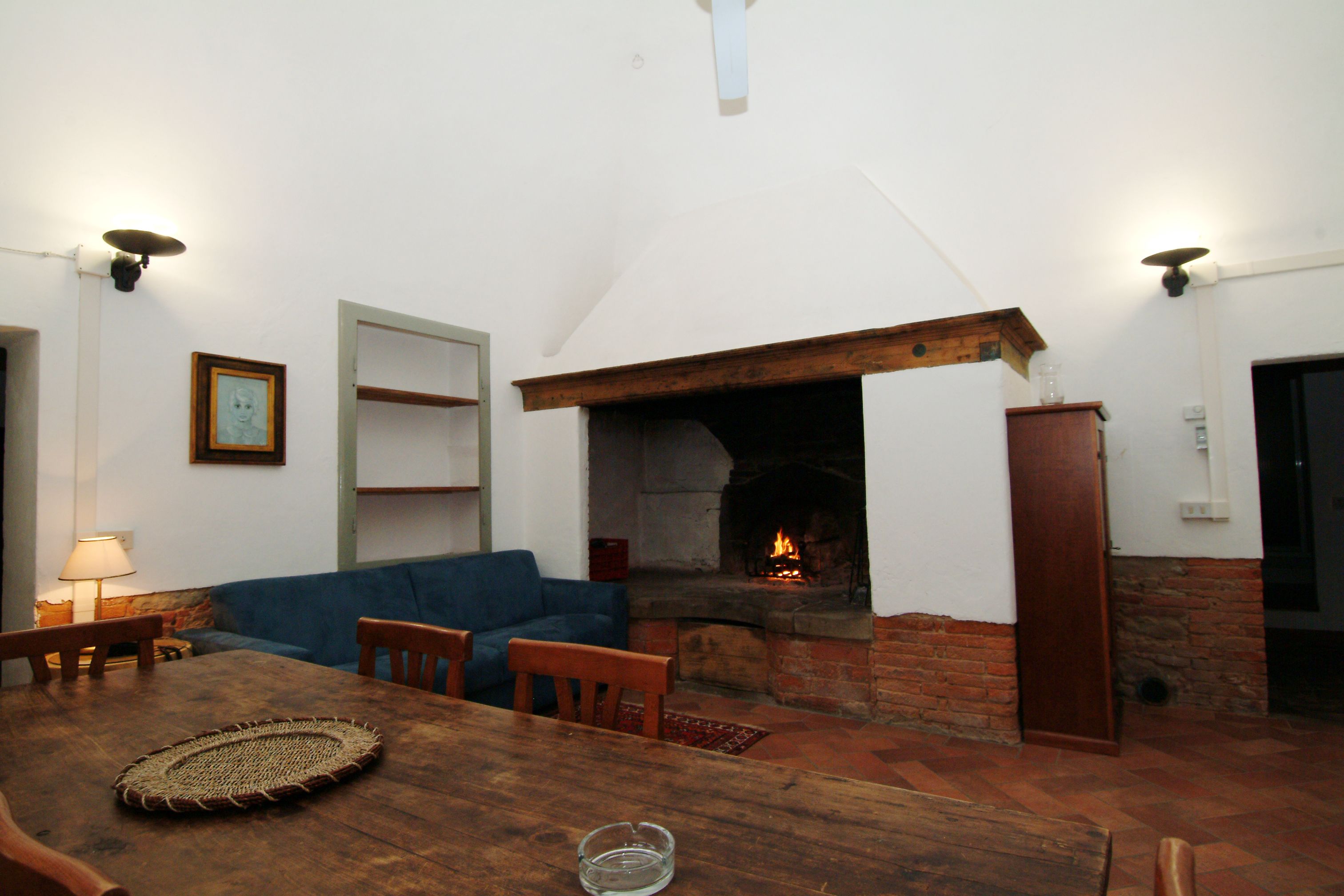 A cozy living room with a fireplace, wooden furniture, and a blue sofa.