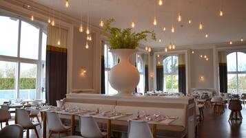 Ein Restaurant mit einem langen Esstisch, mehreren Stühlen und hängenden Glühbirnen.