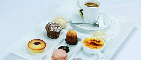 A tray of assorted pastries and a cup of coffee on a white table.
