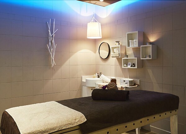 A room with a bed, a bedside table, a mirror, and a wall-mounted shelf with toiletries. - Hotel Cosmos & Spa  (Contrexéville)