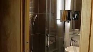 Baño con cabina de ducha de vidrio, lavabo y espejo.