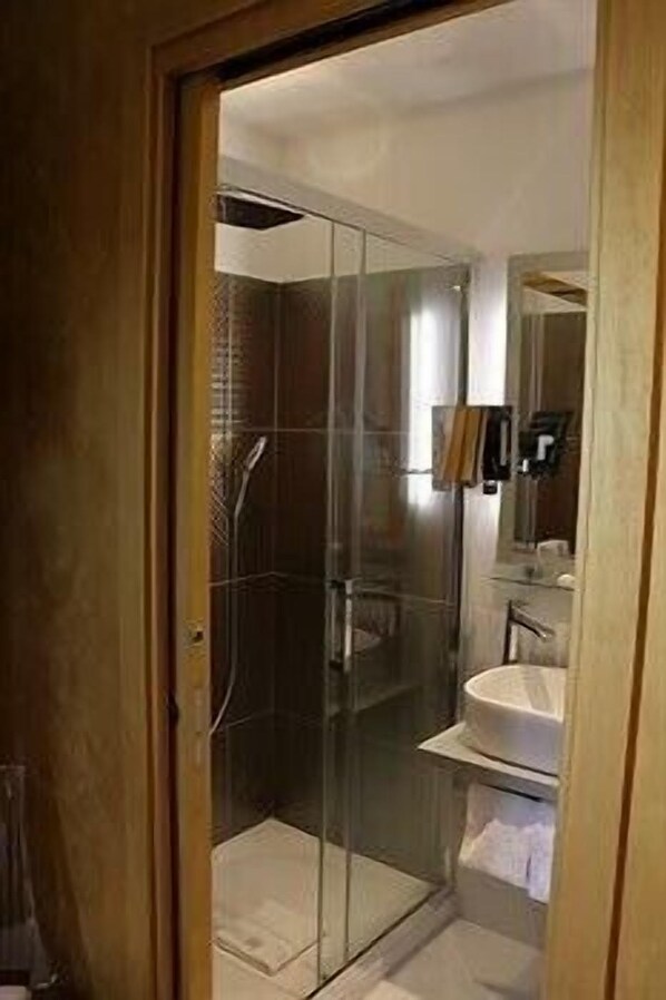 Une salle de bain avec une douche à parois de verre, un lavabo et un miroir.