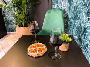 A table with two wine glasses and a plate of food, surrounded by potted plants and a chair. - Hôtel Boutique Richelieu Lyon Gare Part Dieu (Lyon)
