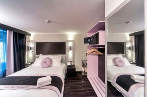 Habitación de hotel con dos camas, un espejo, un escritorio pequeño y un armario.