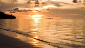 A beach at sunset with calm waters reflecting the sky. - Aqua Resort Club Saipan (Saipan)