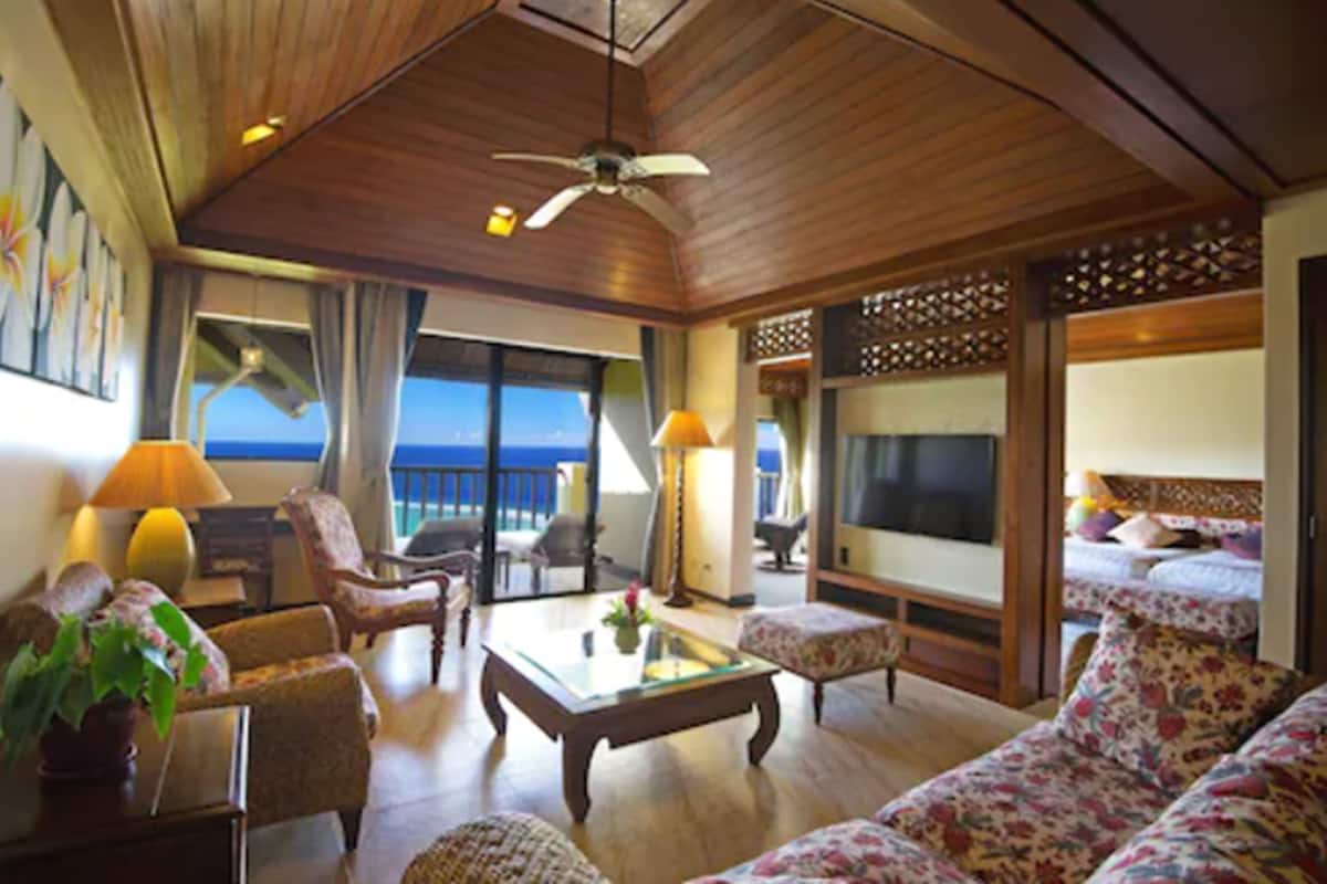 Ein geräumiges Wohnzimmer mit großem Fernseher, bequemen Sitzgelegenheiten und Blick auf den Ozean.