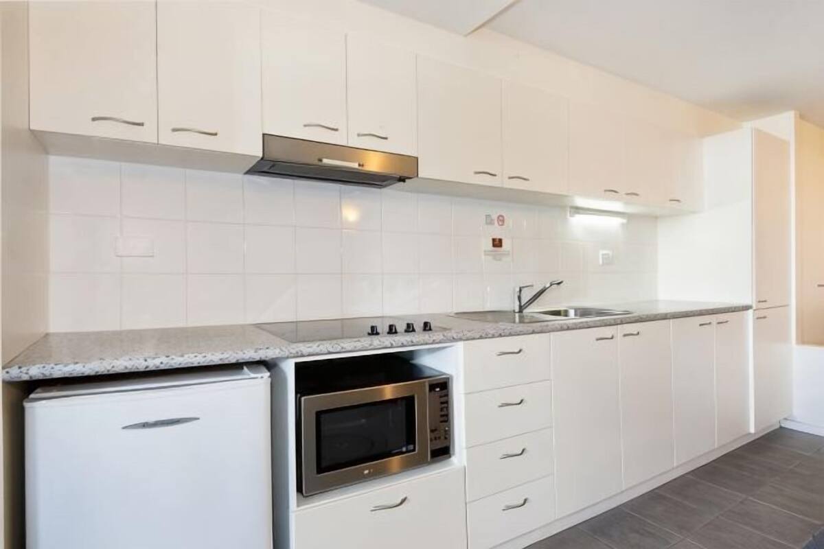 Een keuken met witte kasten, een roestvrijstalen oven en een granieten aanrecht.