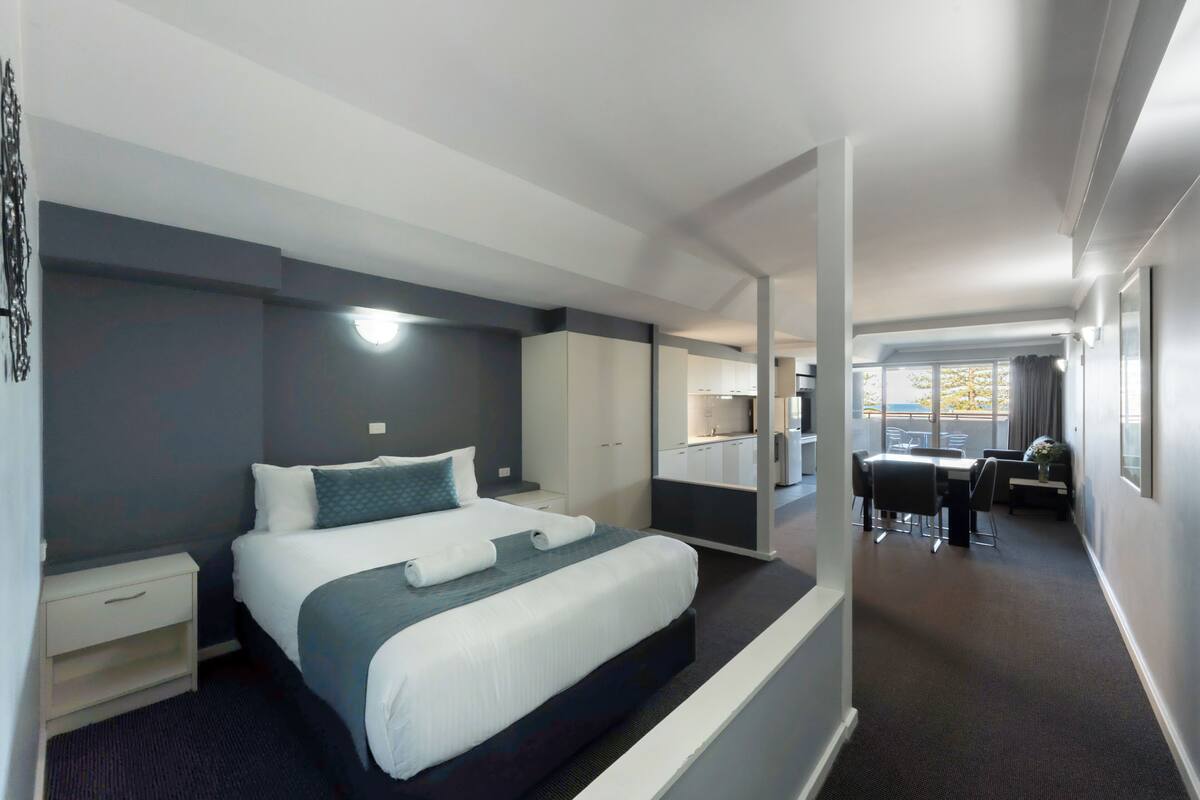 Een moderne hotelkamer met een groot bed, een bureau en uitzicht op de stad.