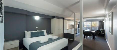 A modern hotel room with a large bed, a desk, and a view of the city.