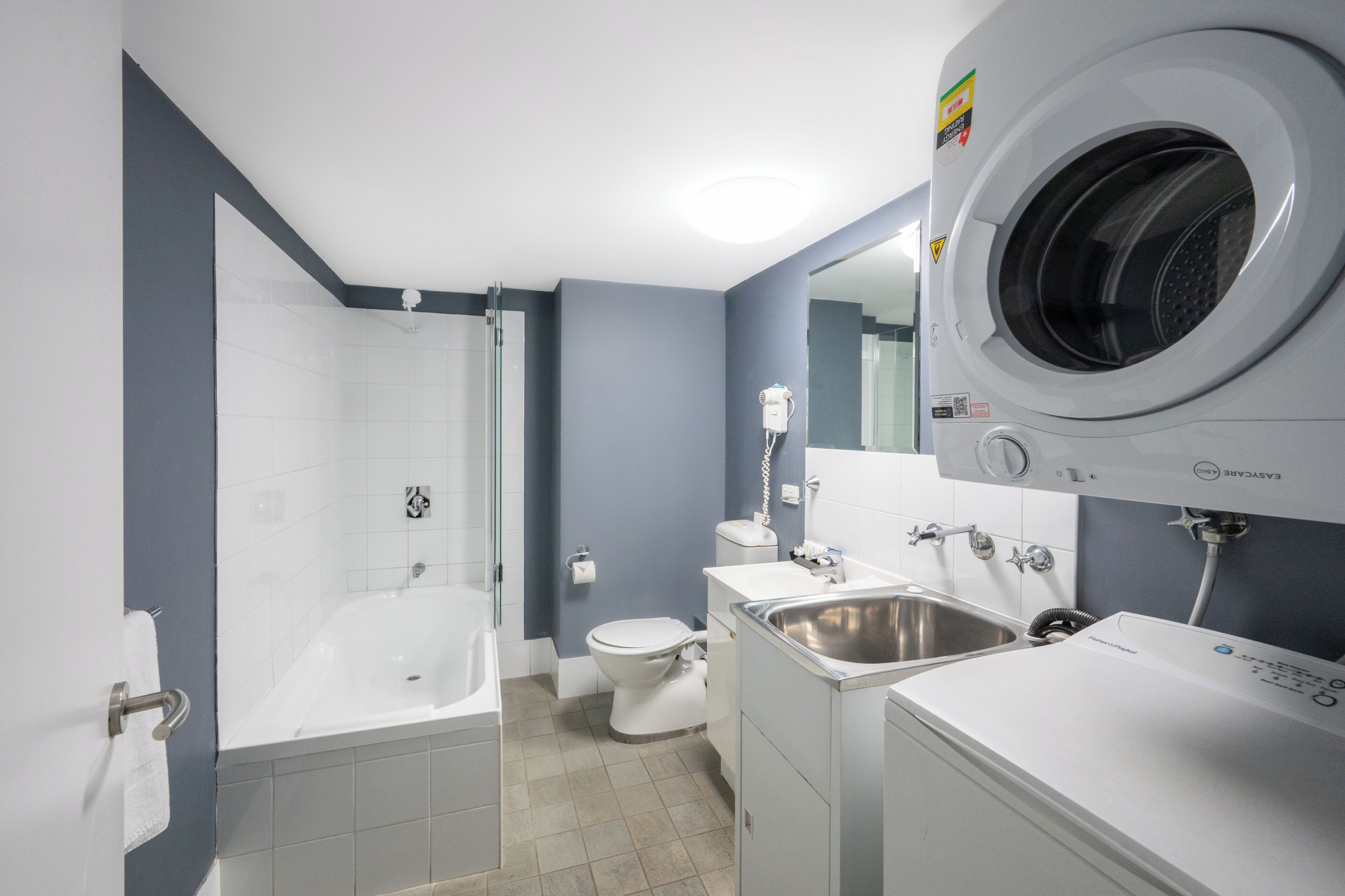 A modern bathroom with a bathtub, toilet, sink, and a front-loading washing machine.