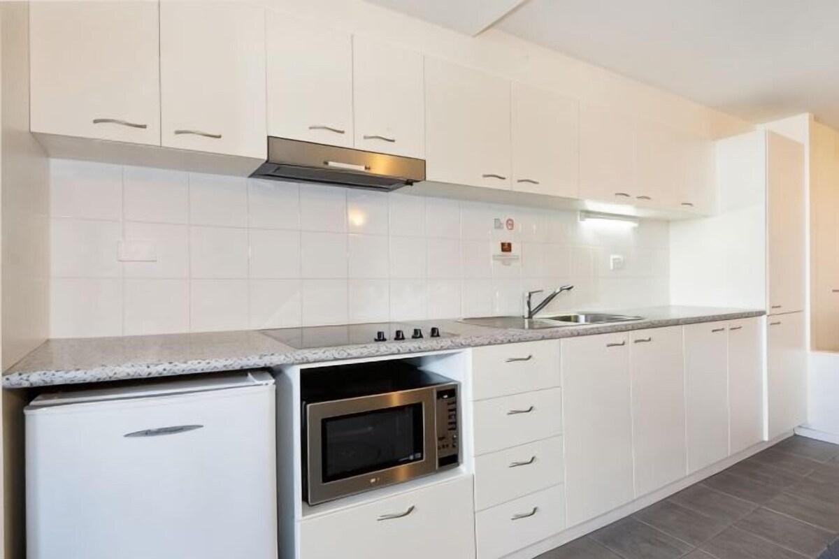 Een keuken met witte kasten, een roestvrijstalen oven en een granieten aanrecht.