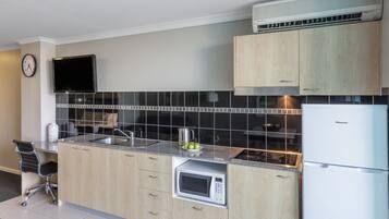 Una cocina moderna con armarios de madera, microondas empotrado, pileta de acero inoxidable y refrigerador Hisense.