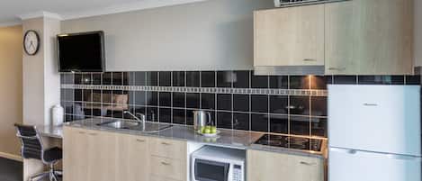 Eine moderne Küche mit Holzausstattung, einer eingebauten Mikrowelle, einem Edelstahl-Spülbecken und einem Hisense-Kühlschrank.