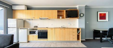 A modern kitchen with wooden cabinets, a microwave, a refrigerator, and a stove. There is a dining table and chairs in the adjacent dining area.