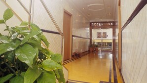 Un área de recepción con piso de mármol, un mostrador de recepción y una puerta que da a otra habitación.