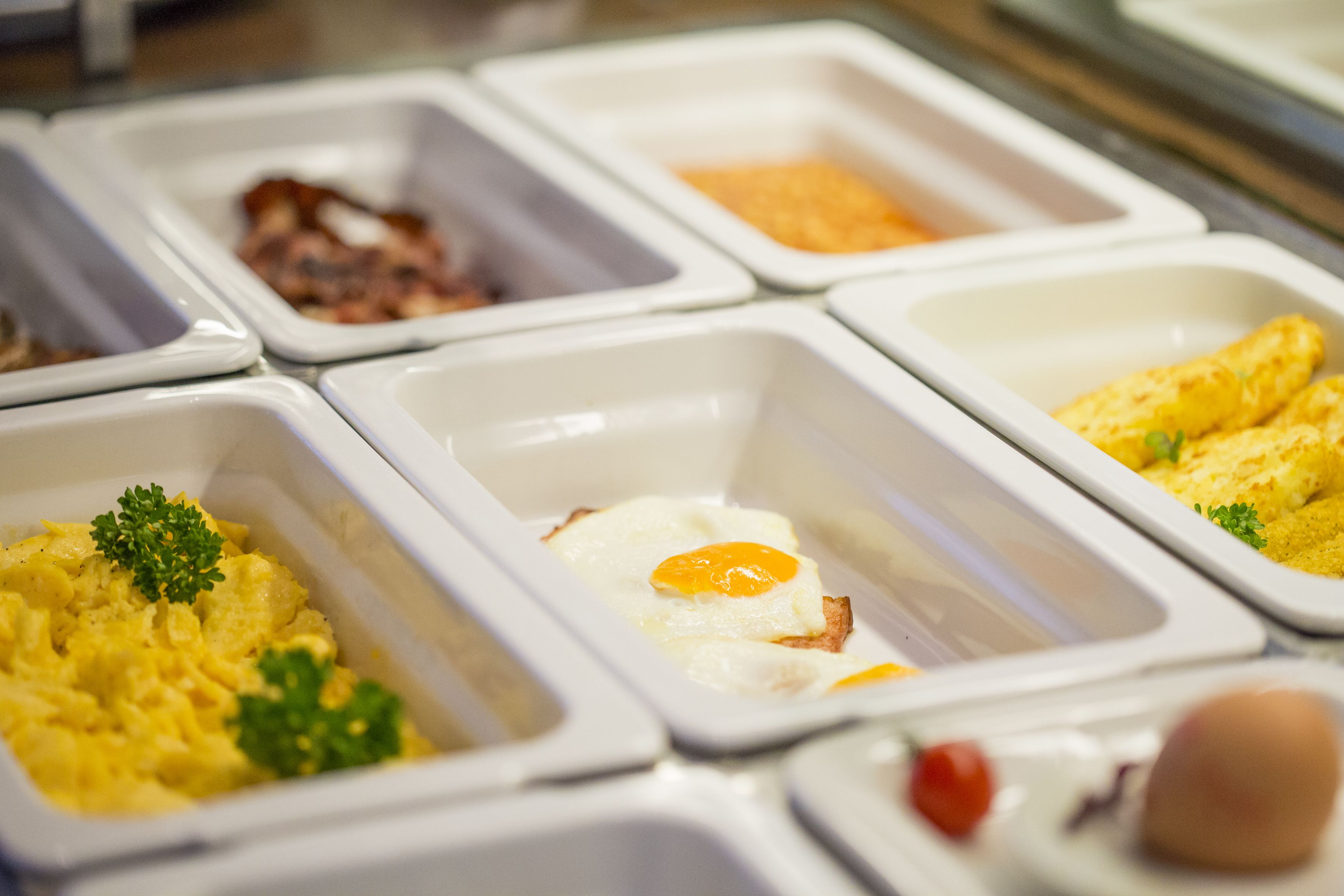A buffet with various food options including scrambled eggs, bacon, and other dishes.