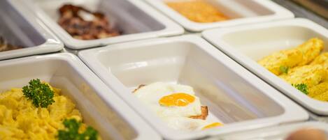 A buffet with various food options including scrambled eggs, bacon, and other dishes.