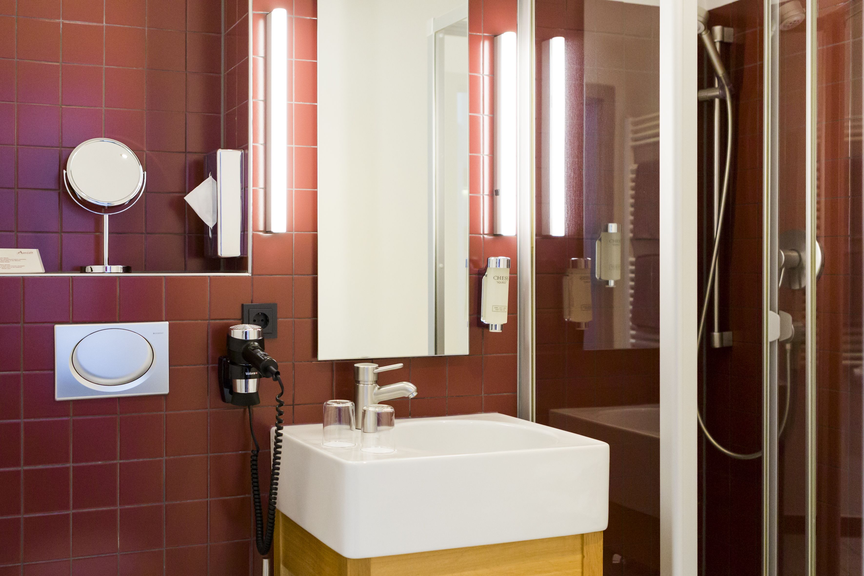 A bathroom with a white sink, a mirror, and a glass-enclosed shower.