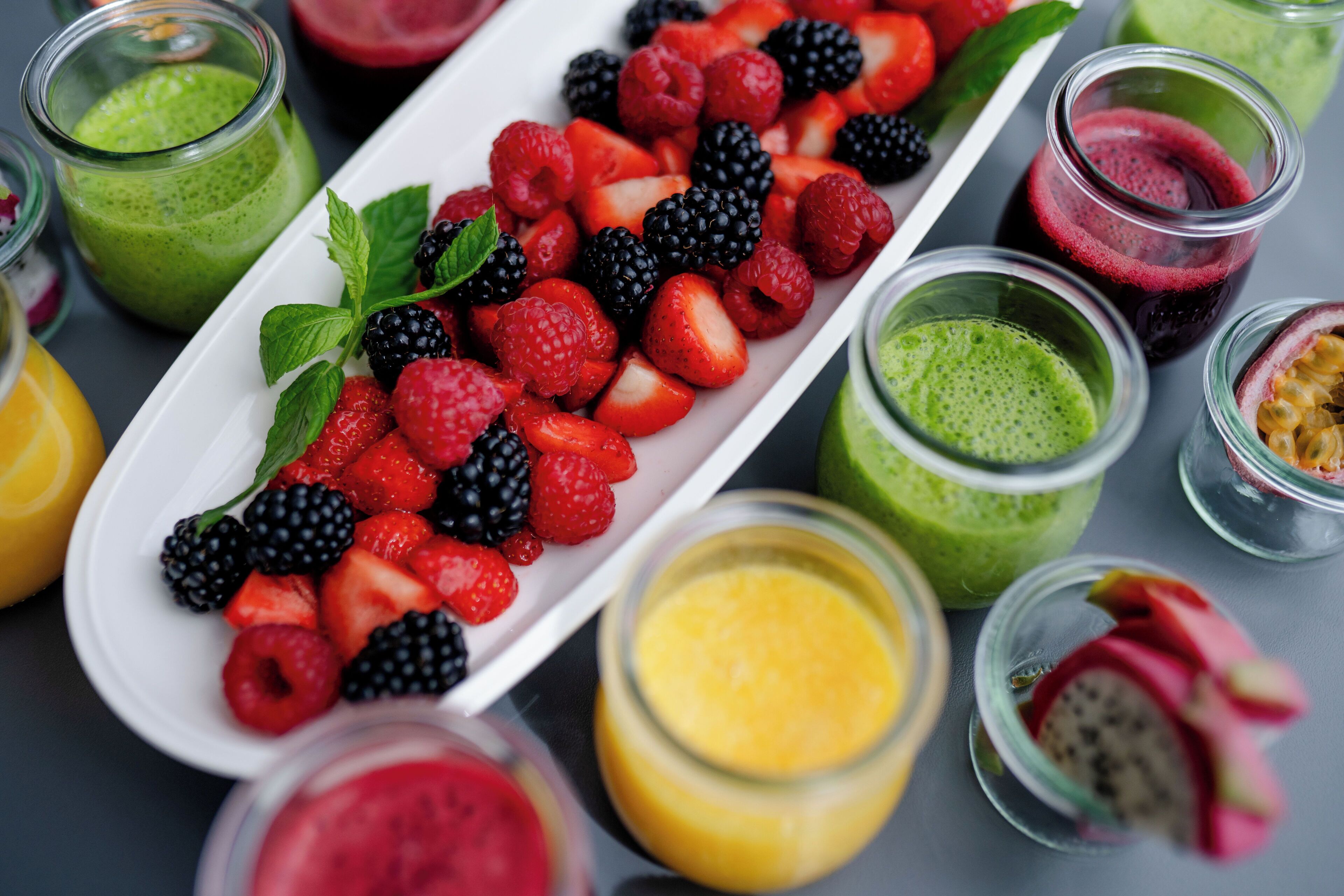 Une variété de fruits frais et de smoothies présentés sur un plateau.