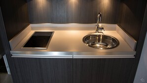 A modern kitchen with a stainless steel sink, a built-in stovetop, and wooden cabinetry.