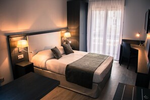 A modern hotel room with a large bed, bedside lamps, a desk, and a chair. - Séjours & Affaires Aix-en-Provence Mirabeau (Aix-en-Provence)