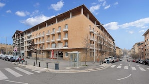 A multi-story building with balconies, a pedestrian crossing, and a bus stop.