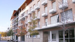 A multi-story building with balconies, a covered entrance, and outdoor seating.