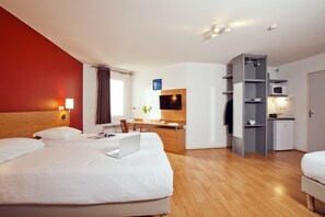 Una camera d'albergo con un letto, una scrivania e angolo cottura.
