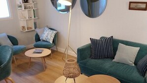 En moderne stue med turkise møbler, et rundt sofabord og en gulvlampe.