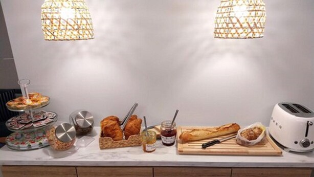 Morgenmadsbuffet med kager, brød og en brødrister på en marmorbordplade.