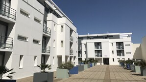 En moderne bygning med flere etager, altaner og en belagt gårdsplads.