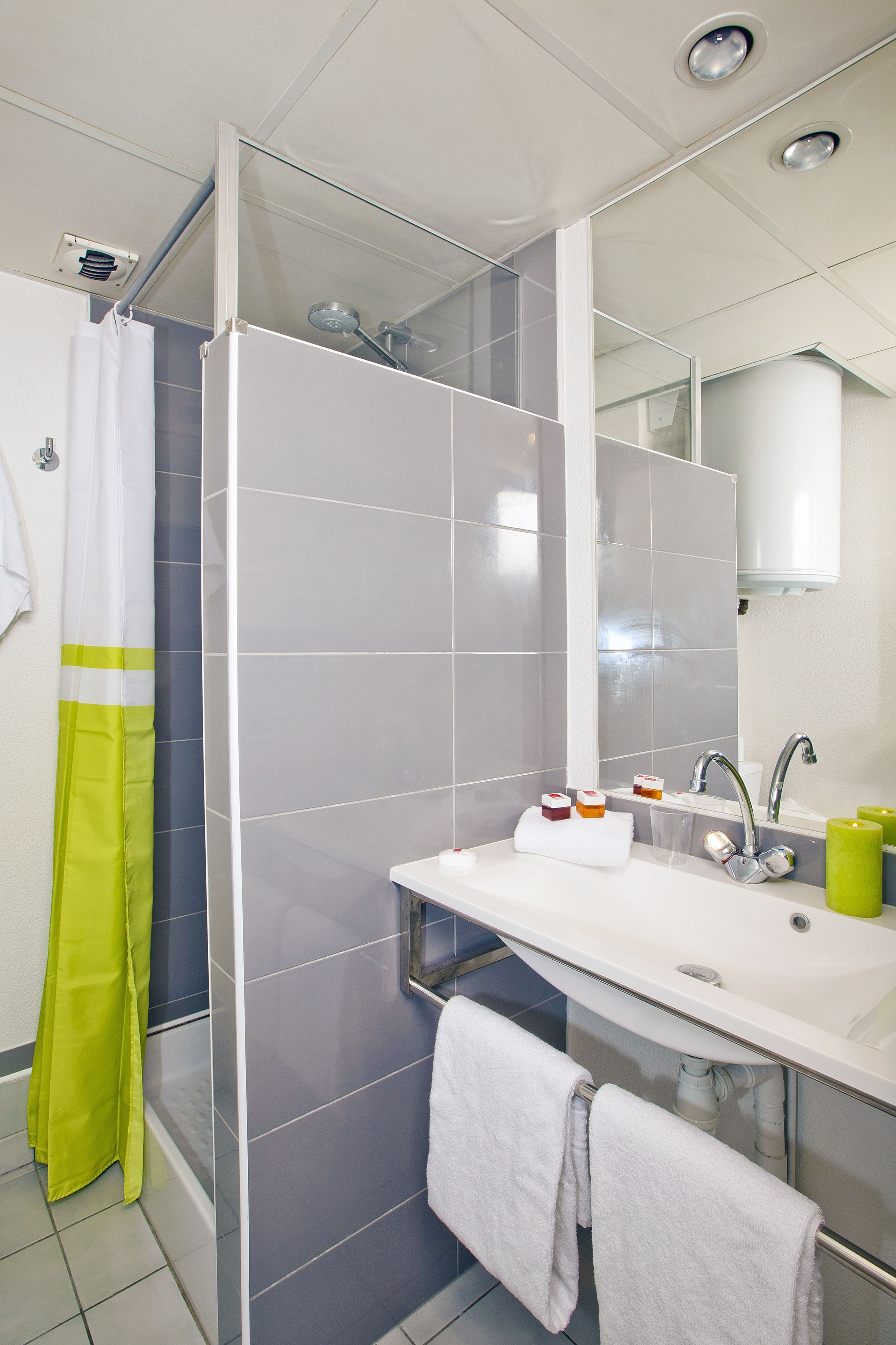 Een moderne badkamer met een douchecabine van glas, een witte wastafel met spiegel en een handdoekrek.