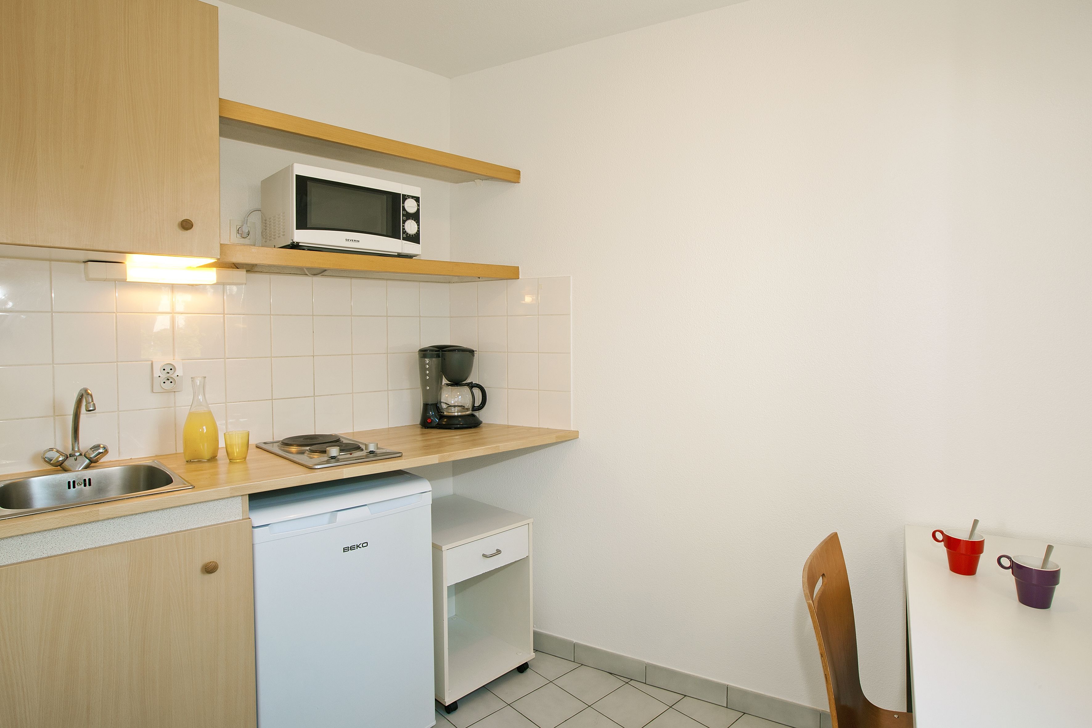 A compact kitchen with a microwave, coffee maker, and a dishwasher.