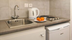 A compact kitchen with a sink, a microwave, a kettle, and a small refrigerator.