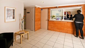 A reception area with a reception desk, a wooden bench, a framed picture on the wall, and a black chair.