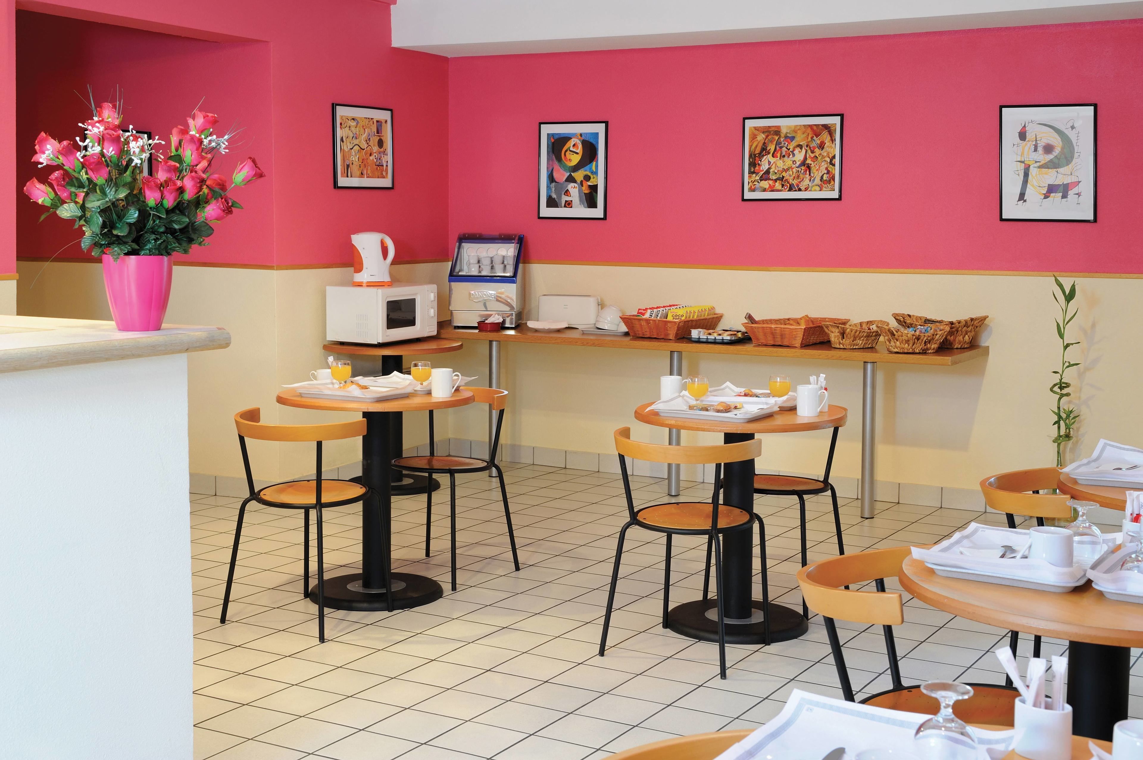 A dining area with tables and chairs, a coffee machine, and a vase of flowers.